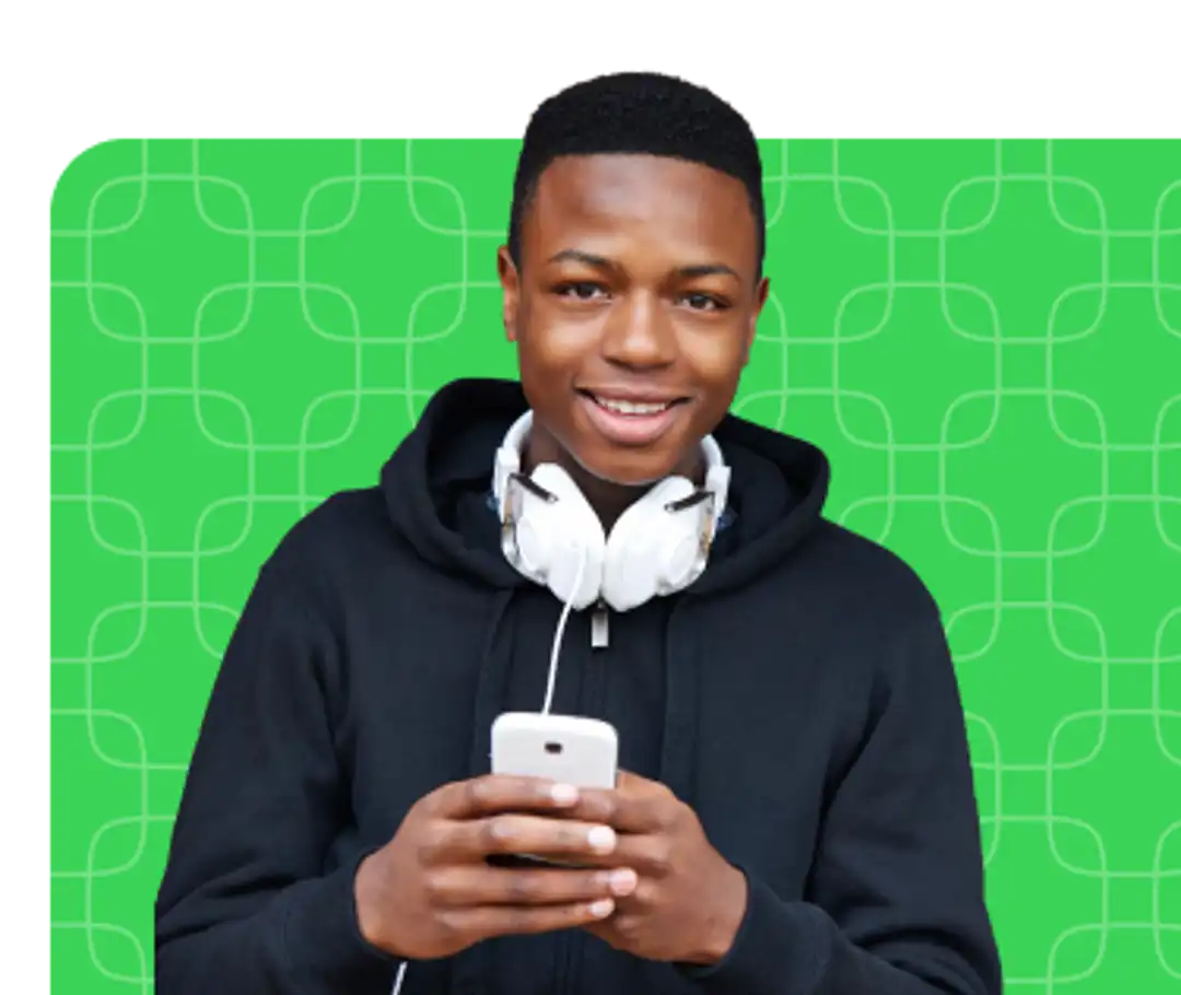 Young man with headphones around his neck smiling and holding his phone