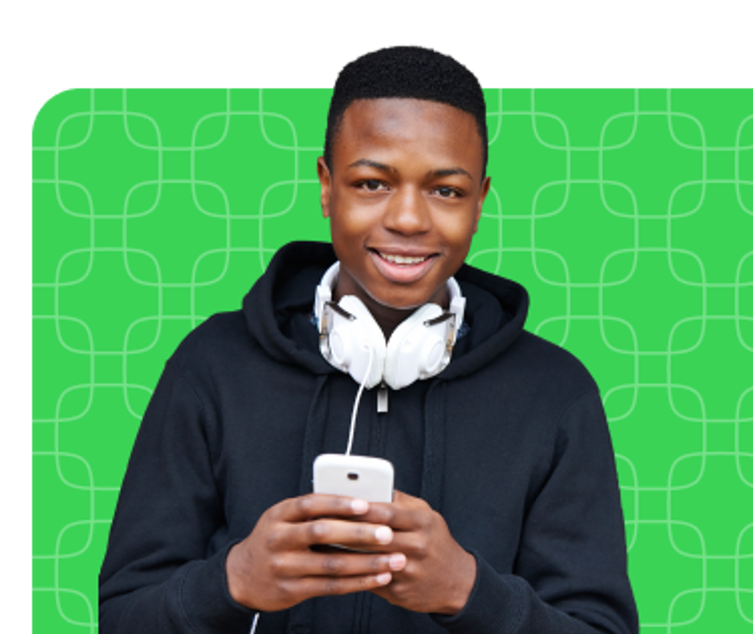 Young man with headphones around his neck smiling and holding his phone